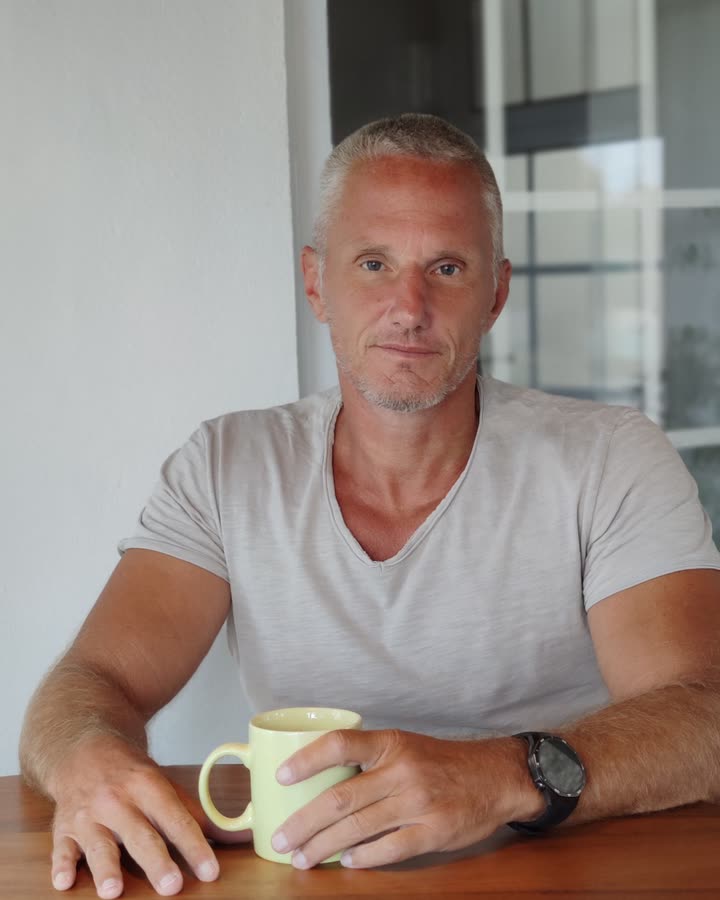 Stefan Scheurer at a wooden table, holding a cup